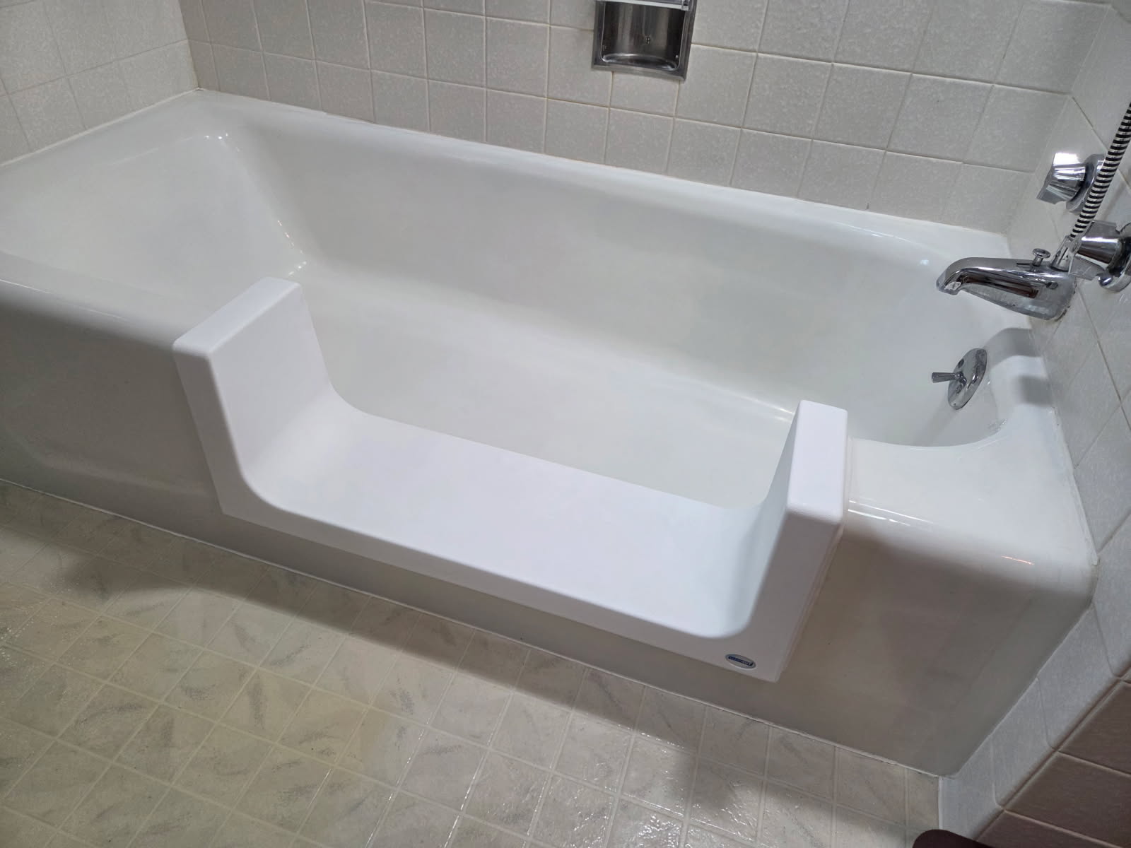 The Step conversion with a low opening in a white bathtub surrounded by gray tile